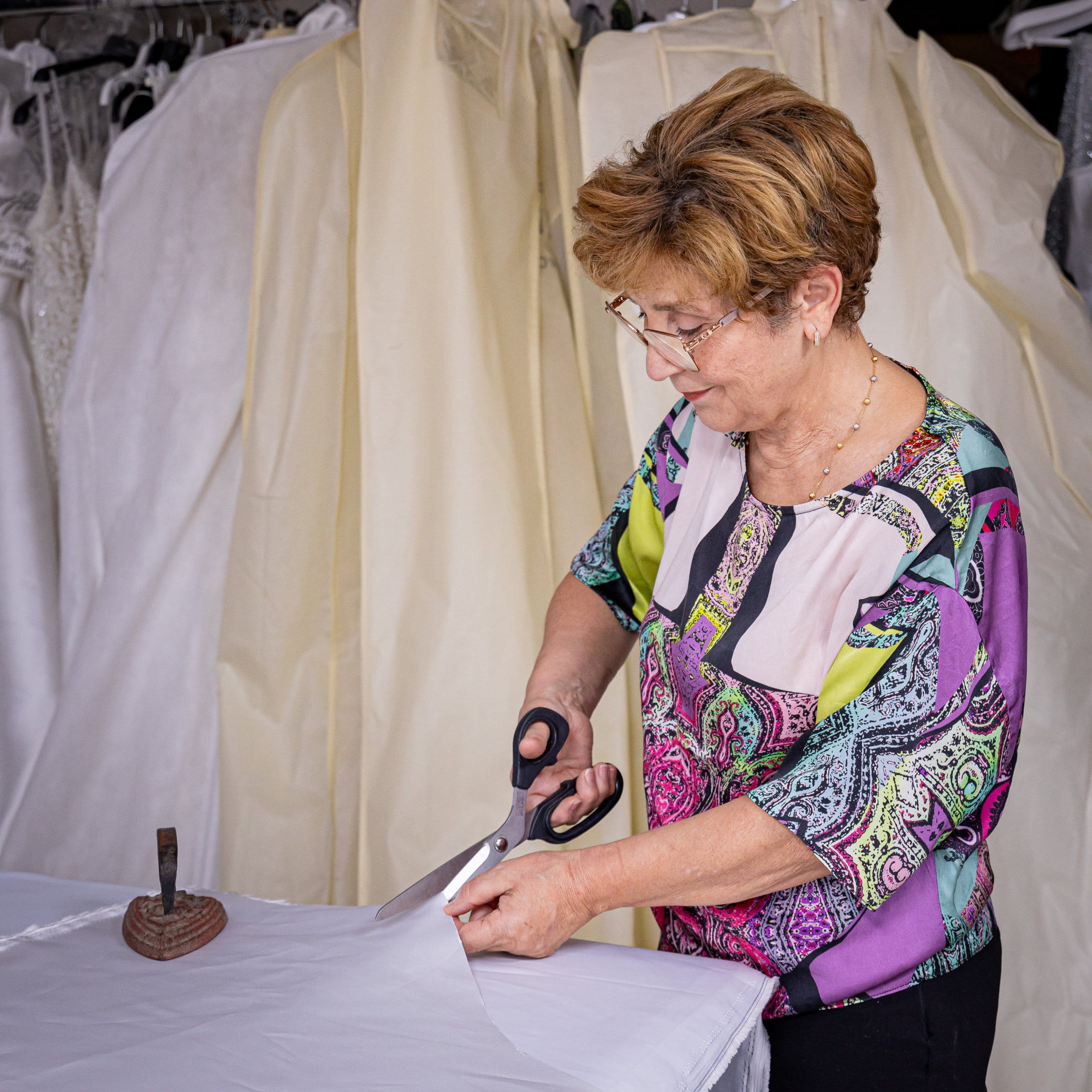 Sarta di Atelier Crilù taglia il tessuto davanti agli abiti da sposa